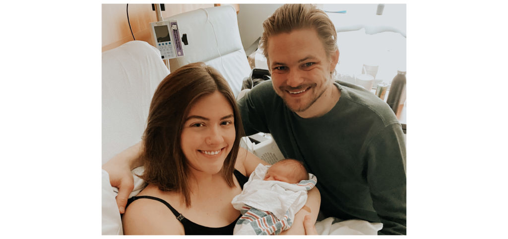 A new mom and dad pose in a hospital room with their newborn baby