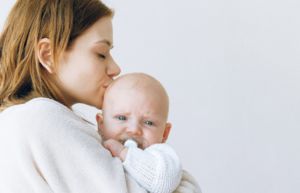 Mother holding and kissing her baby