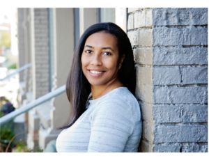 Dr. Carrie Dennie leans against a brick wall