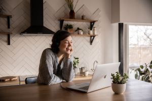 Woman sits at her kitchen counter in front of her laptop