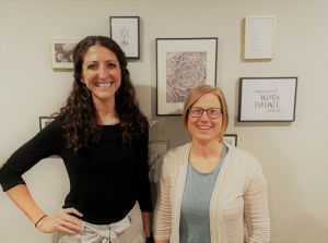 Rise Wellness practitioners standing together in front of a wall of picture frames