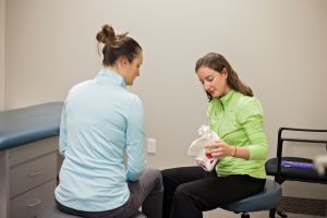 Chiropractor educates woman about the pelvis holding a skeleton hip