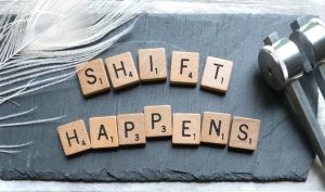 Scrabble pieces on a slate spelling out, "Shift Happens"