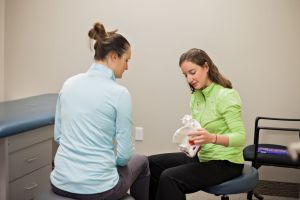 Physician holds a skeletal pelvis while educating a patient in a doctor's office