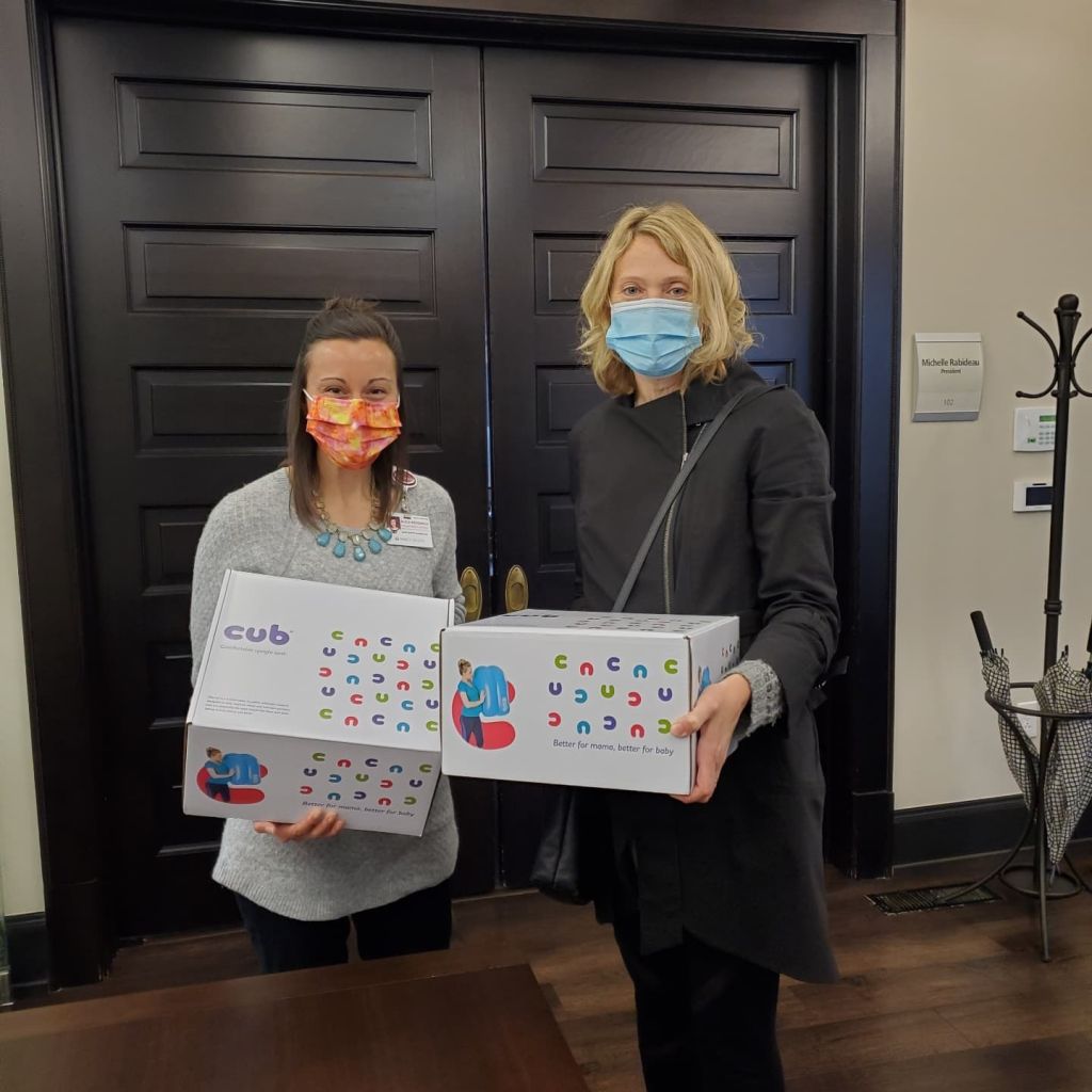 Kristin Revere and another woman holding cub boxes and wearing masks in an office together