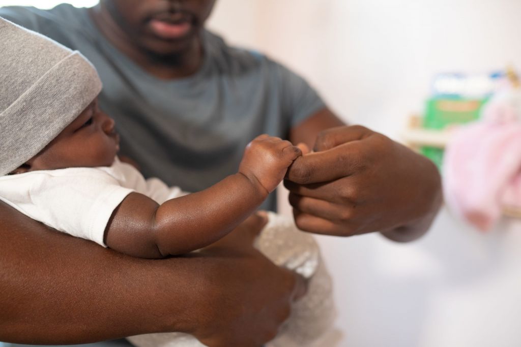 Father holding his baby while baby holds onto his finger