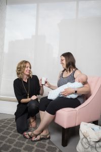 Kristin of Gold Coast Doulas hands a mug to a mother holding her infant