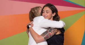 Kristin and Alyssa of Gold Coast Doulas hugging in front of a colorful wall