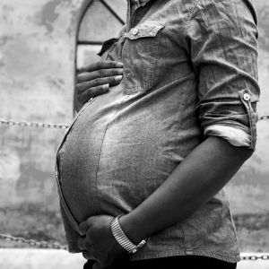 Black and white image of a pregnant mother holding her belly
