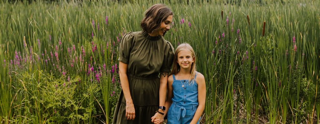 Alyssa Veneklase holds her daughter's hand in front of a field