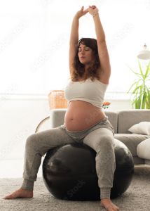 Pregnant woman sitting on an exercise ball doing a stretch