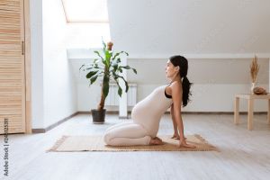 Pregnant woman doing a yoga pose on a mat