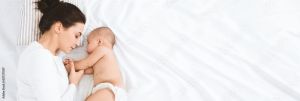 Infant and mother lying together on a white sheet