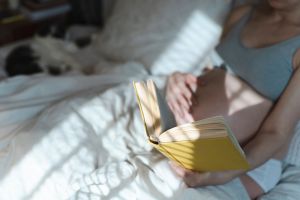 Pregnant woman rests in a bed while reading a book