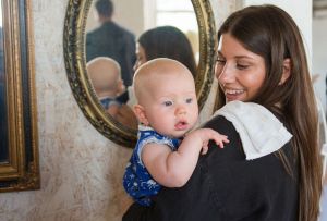 Mother holding her infant with a mirror in the background