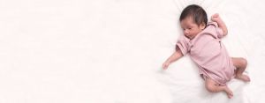 Newborn infant lays on a white bed