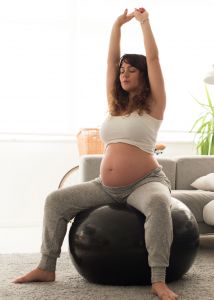 Pregnant woman on a birthing ball stretching