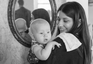 Black and white image of a mother holding her infant with a mirror in the background