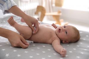 Infant baby laying on a changing pad having their diaper changed