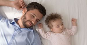 Father sleeping next to his sleeping infant