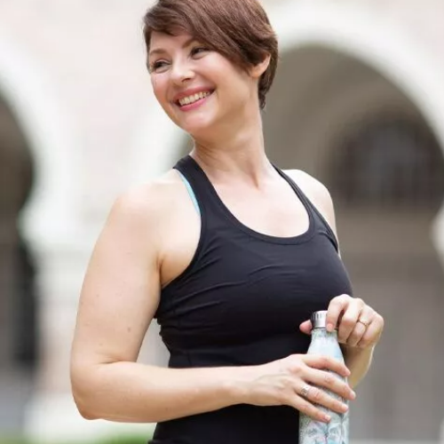 Woman holding a water bottle wearing a black exercise tank top