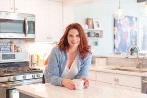 Christine Brown poses in a kitchen holding a coffee mug