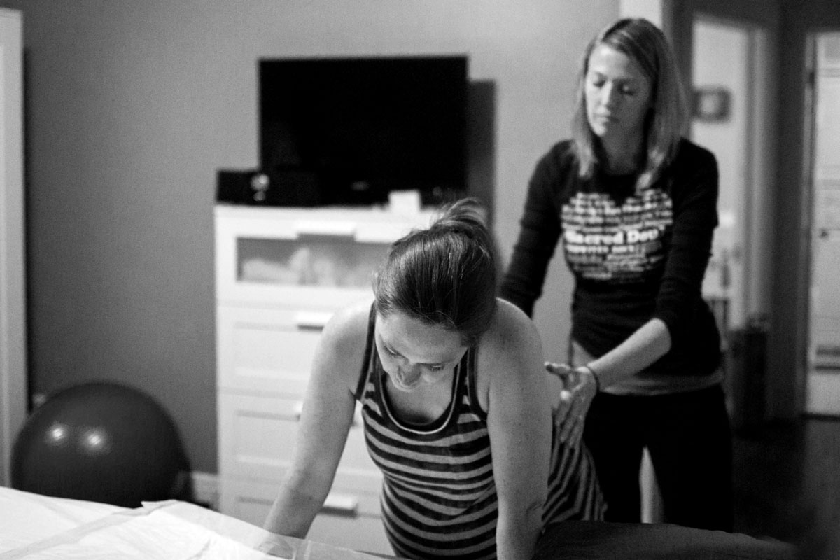 Kristen Revere, birth doula, offers a comforting touch to a laboring mom birthing at her home