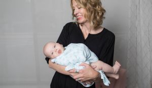 Kristin Revere of Gold Coast Doulas smiles while holding a swaddled infant