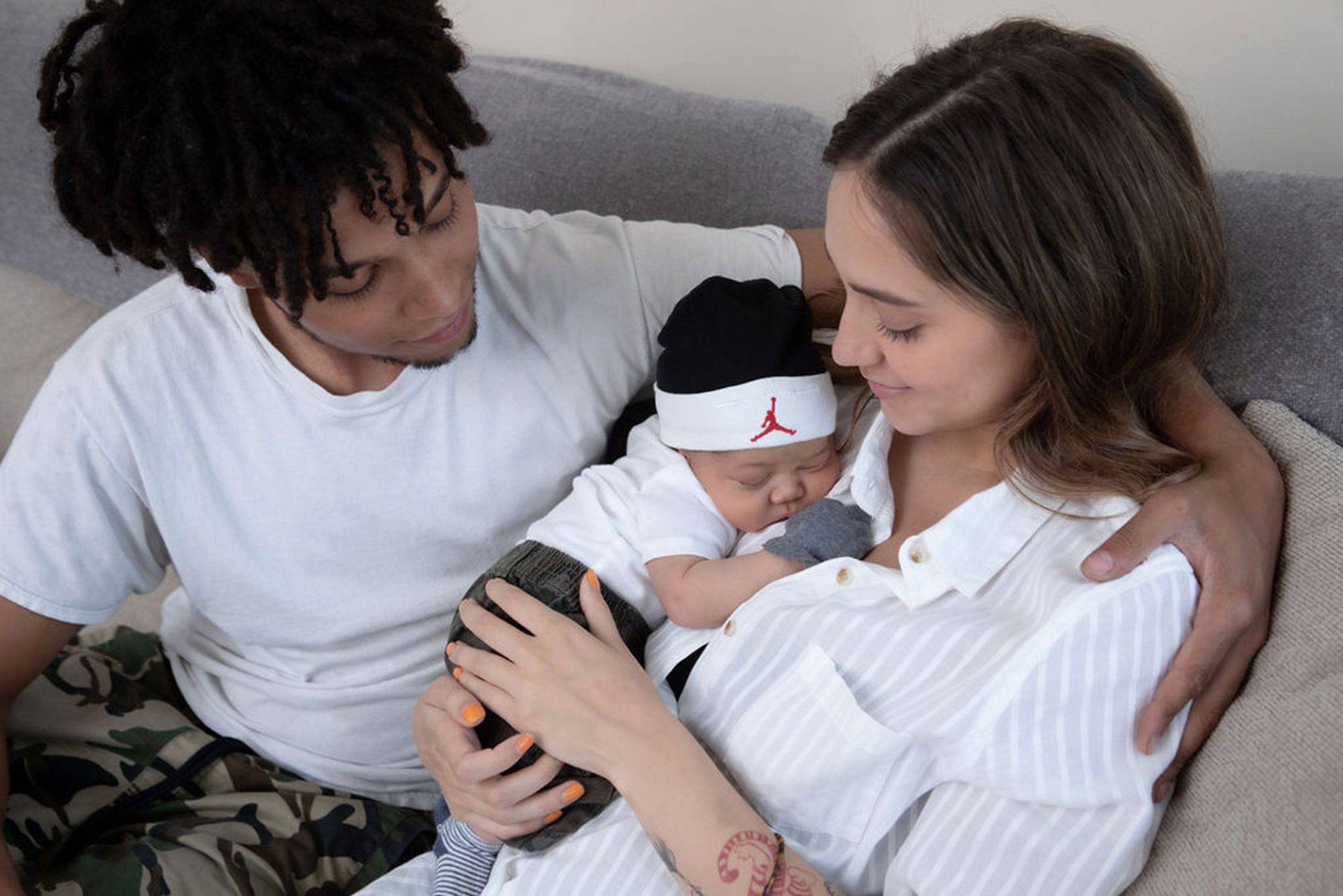 Mother, Father, and newborn snuggled together on a couch