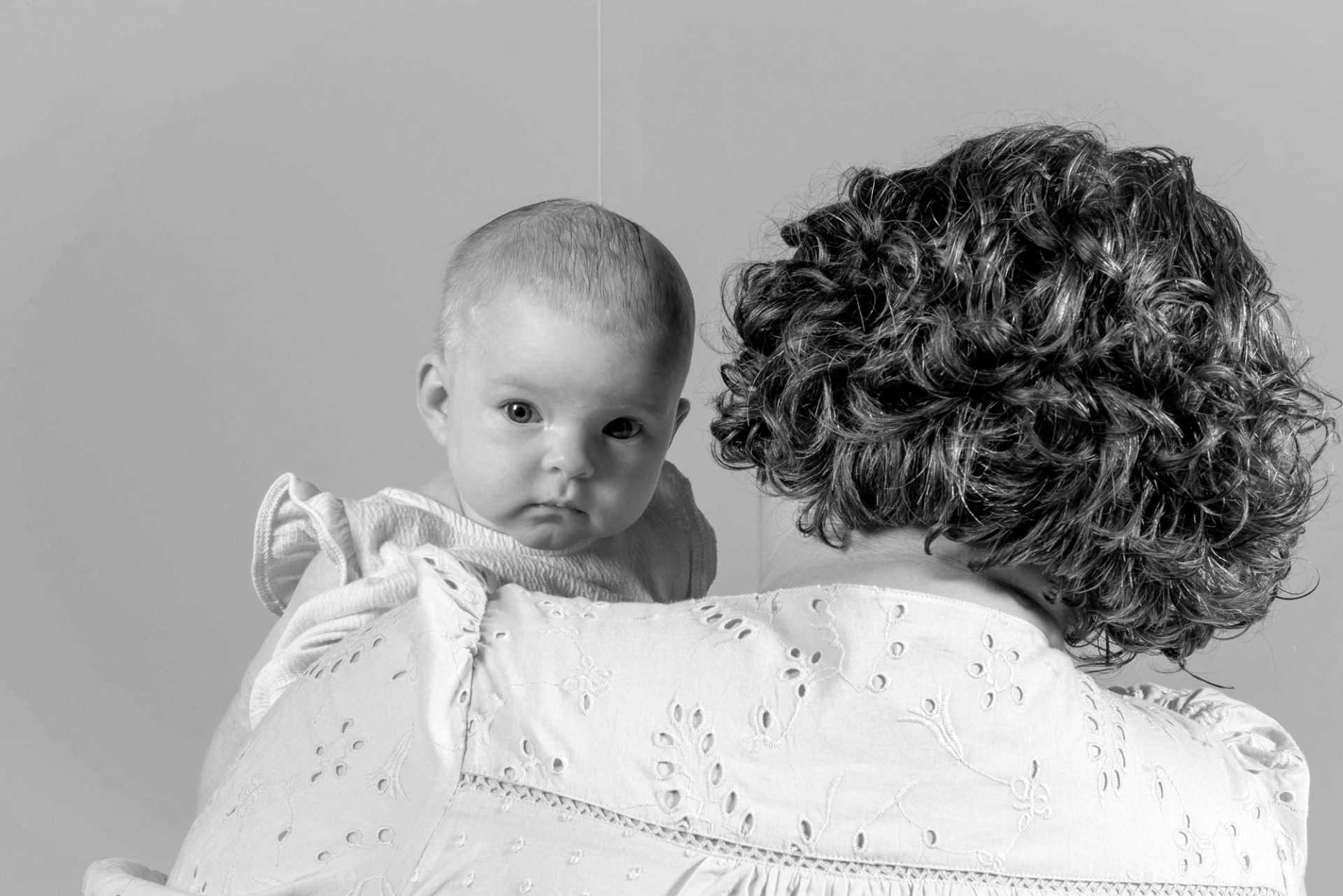 Black and white photo of the back of a woman holding an infant