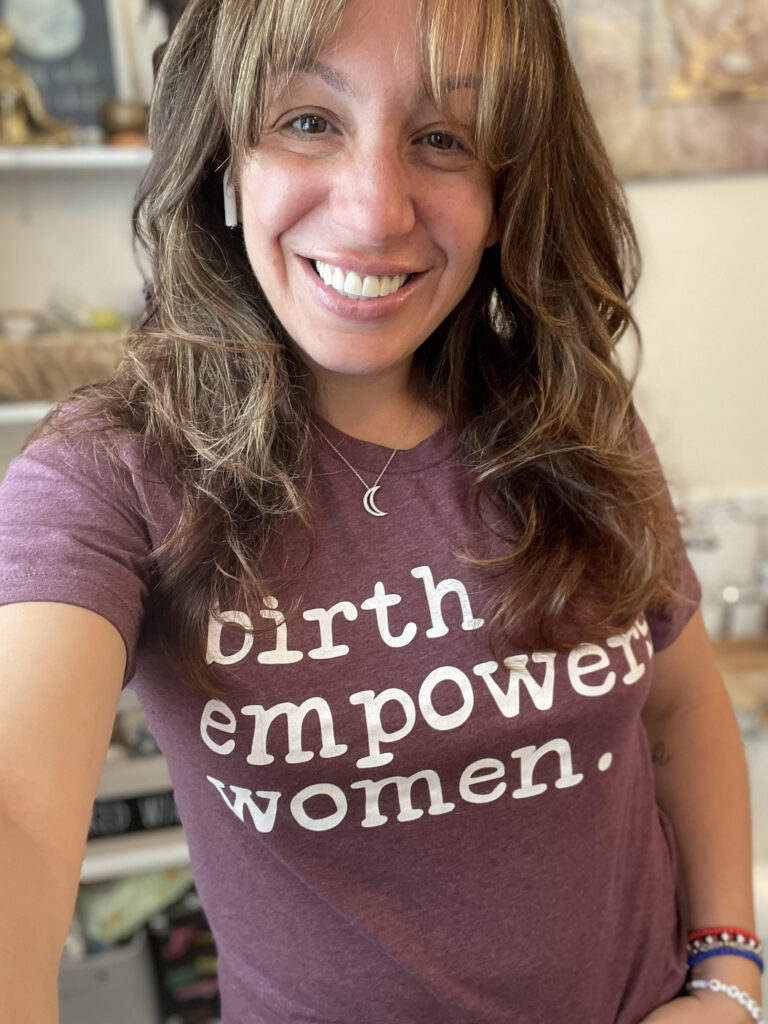 Angela Mancini taking a selfie wearing a "birth empowers women" shirt