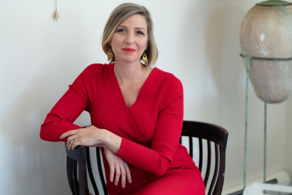 Dr. Burns wearing a red sweater dress sitting in a chair