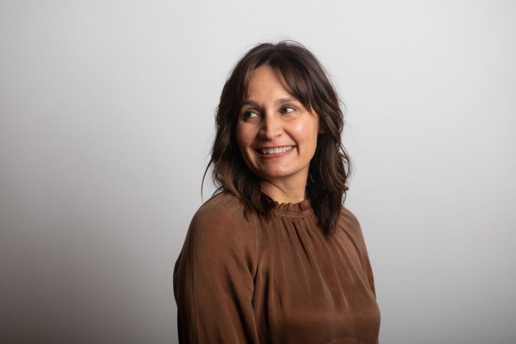 Lisa Newhouse of Gold Coast Doulas wearing a brown blouse with a purple background headshot