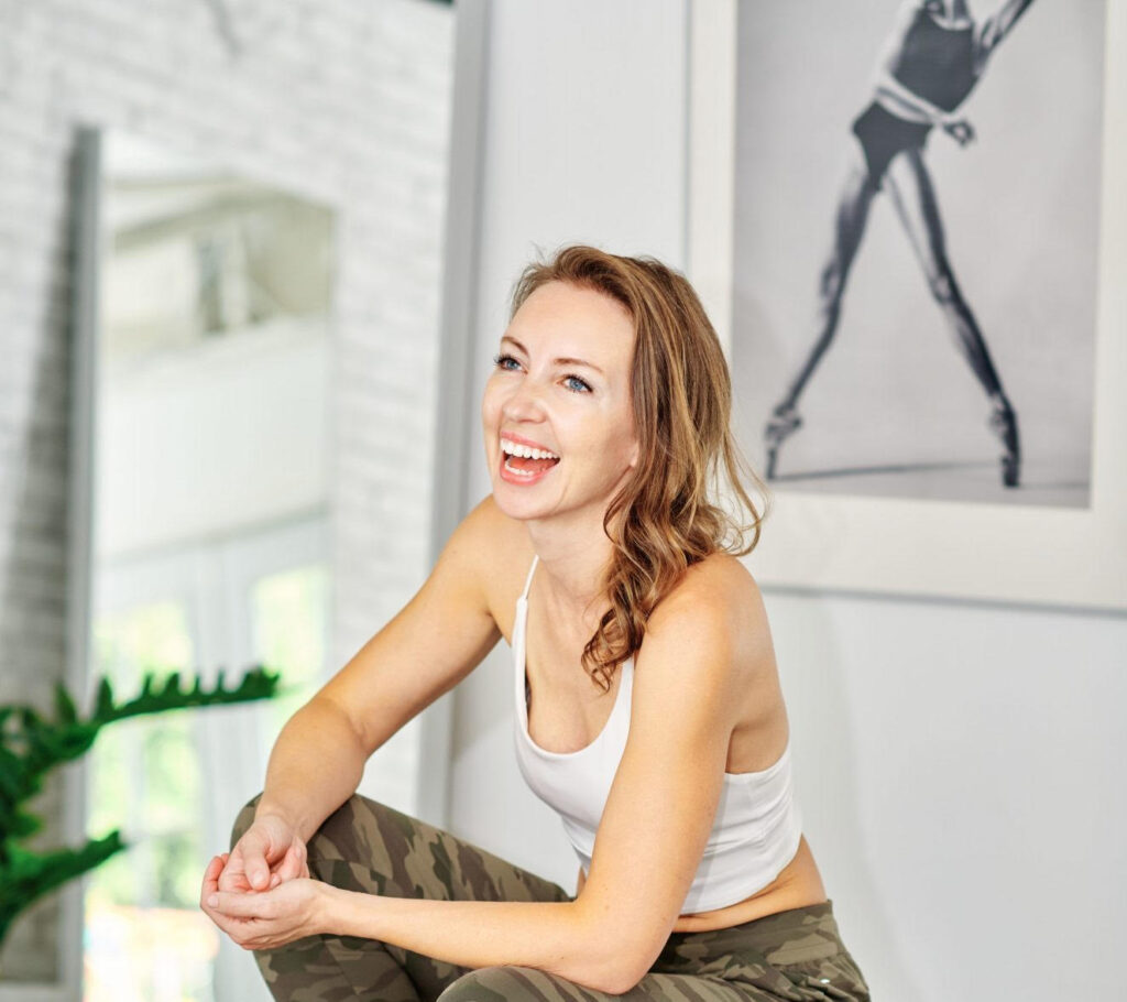 Emma Bromley of Bromley Method wearing a white tank top and camo pants with white walls