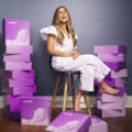 Marnie of Rumbly, a pregnancy subscription box company, sits surrounded by purple Rumbly boxes.