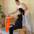 Anna Downs shows a pregnant mom in black clothing how to do stretches