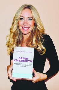 Gina Mundy holds up her book, "A Parent's Guide to a Safer Childbirth" against a pink backdrop