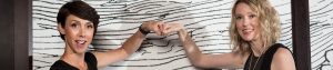 2 women fist bumping on black and white background