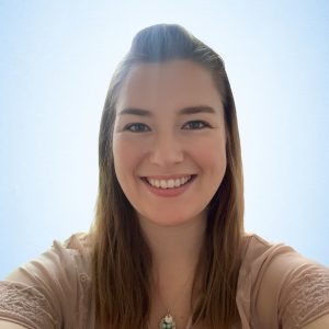 Julia Peterson smiling headshot wearing a tan shirt in front of a blue sky background