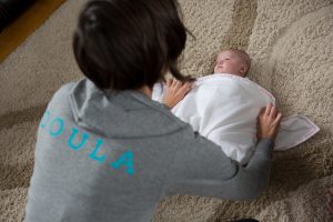 Postpartum Doula swaddling a baby