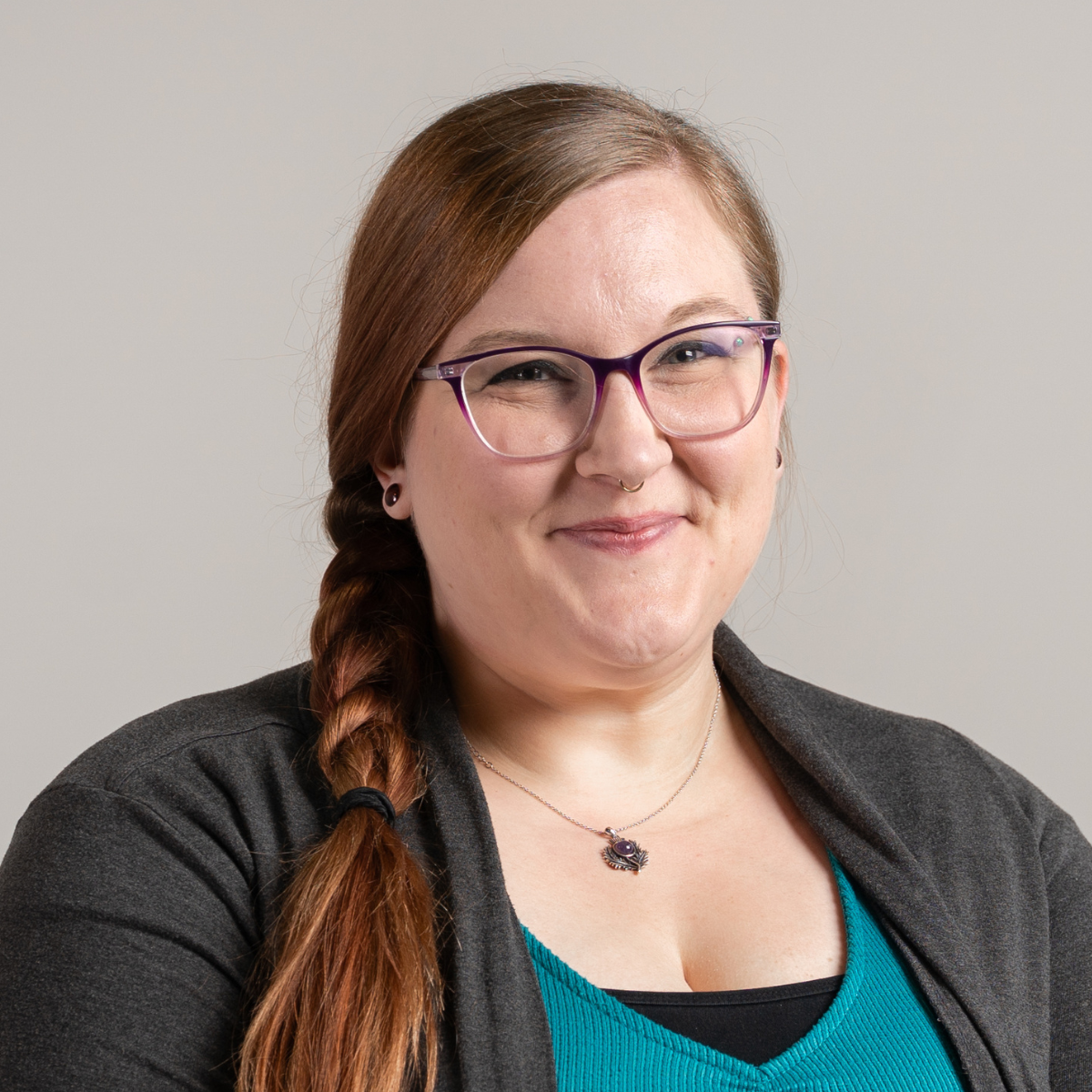 Brianna Soblewski smiling wearing a black cardigan, wearing a teal undershirt in front of a grey background